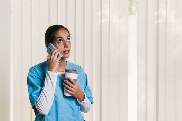istock Young nurse talking on phone and holding coffee 2197236479
