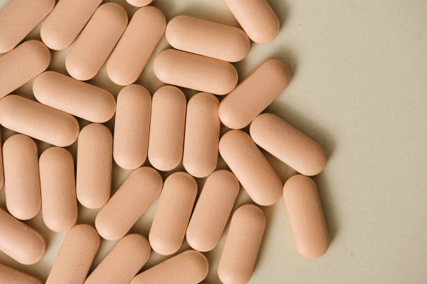 istock Oval pink pills forming a diagonal line on a beige background 2197236488