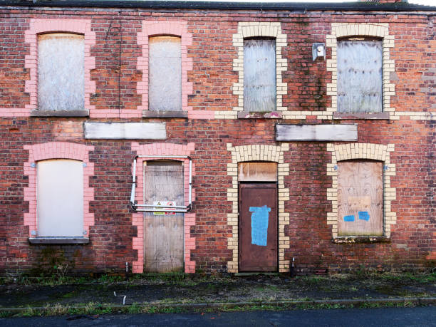 istock A decaying brick terraced houses, featuring boarded-up windows and doors, showing signs of neglect. 2197237100