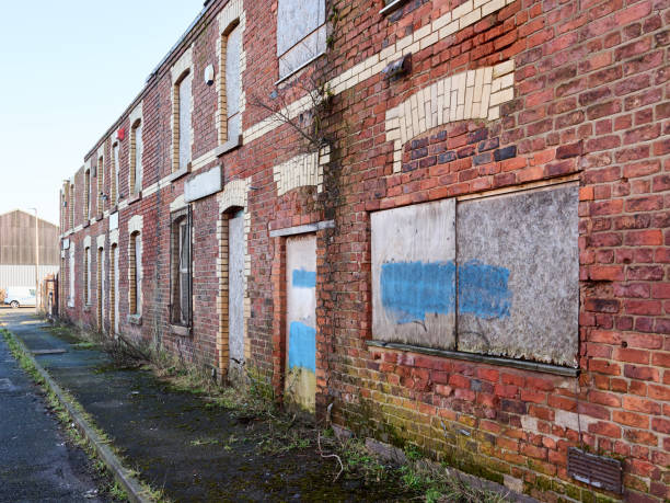 istock Abandoned brick building with boarded windows and overgrown vegetation. 2197237207