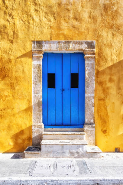 Yellow house with blue wooden door in San Francisco de Campeche, Mexico