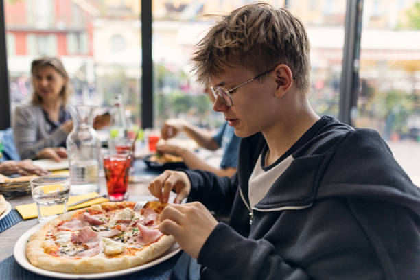 istock Teenage boy eating pizza with ham and mushrooms. 2197237607