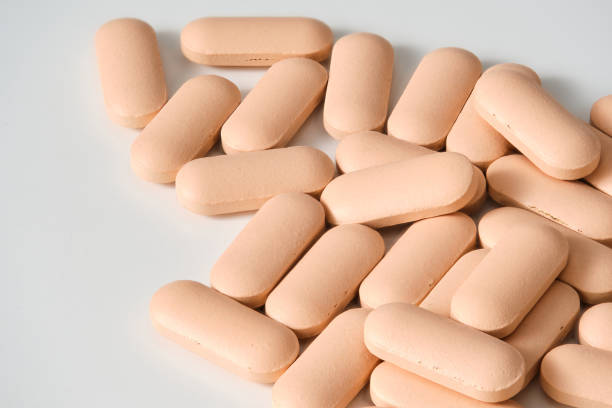 istock Oval Peach Colored Pills Forming a Pile on a White Background 2197238636