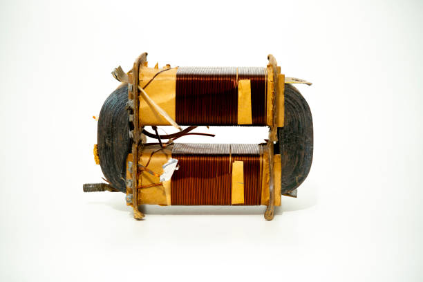 An electric motor coil is positioned on a white background, showcasing its intricate wire winding and metal components, ideal for educational inspection or analysis.
