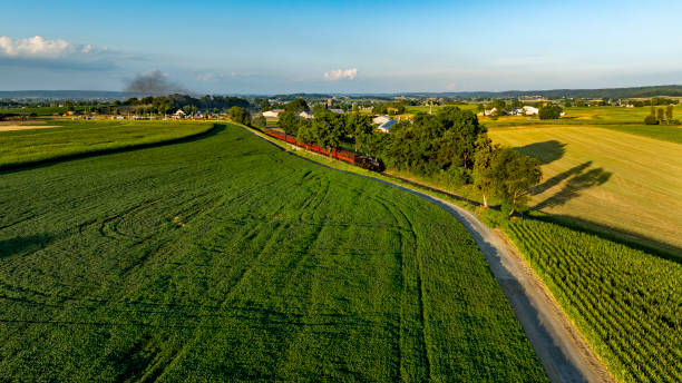 istock Scenic countryside view featuring a vibrant train traveling through lush fields at sunset near a rural town 2197245741