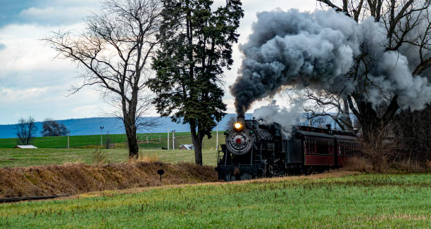 istock Historic Steam Train Traveling Through a Rural Landscape Under a Cloudy Sky 2197245970