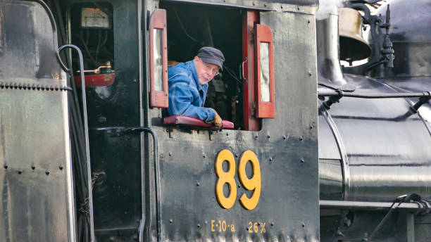 Strasburg, Pennsylvania, USA, December 31, 2024 - James Rice, A dedicated engineer adjusts the controls of a steam engine at a historic railway station, showcasing his expertise in maintaining vintage machinery on an autumn day.