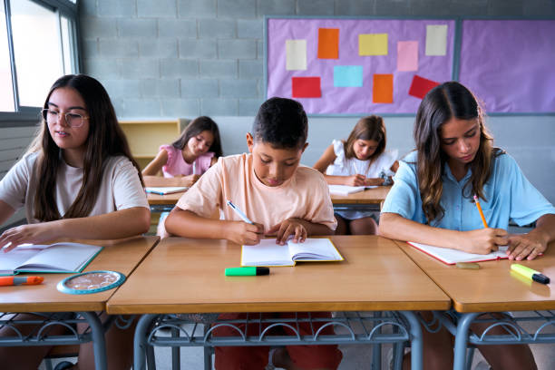 istock Front view of a group of multiracial students working together in a classroom. 2197248863