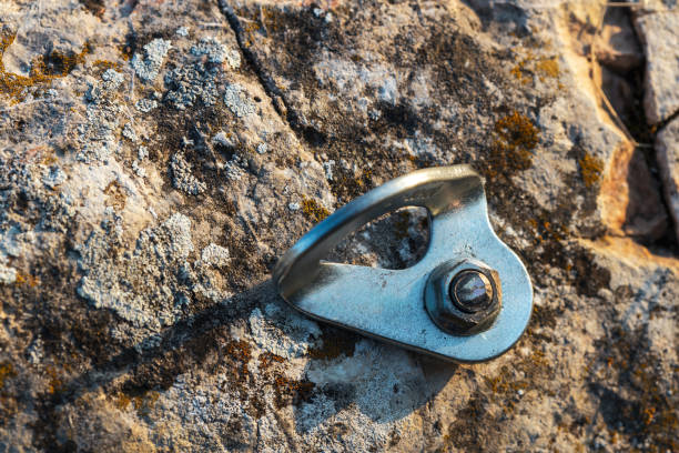 A metal hook is sitting on a rock. The hook is attached to a rope and is used for climbing