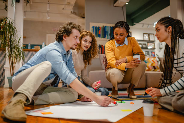 istock multicultural colleagues gather around a large paper on a wooden floor 2197249755