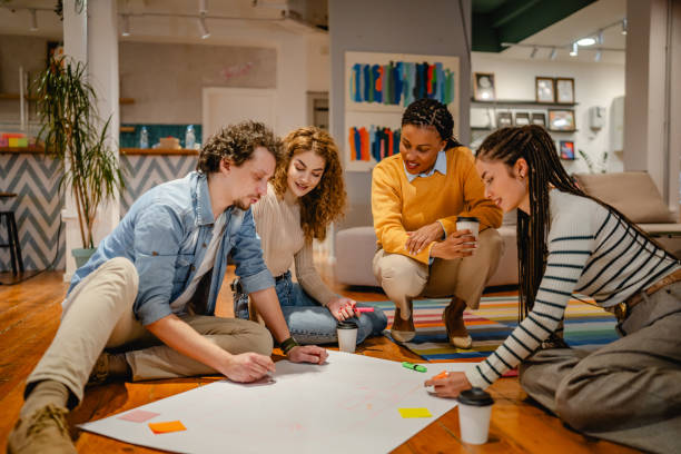 istock multicultural colleagues gather around a large paper on a wooden floor 2197249757