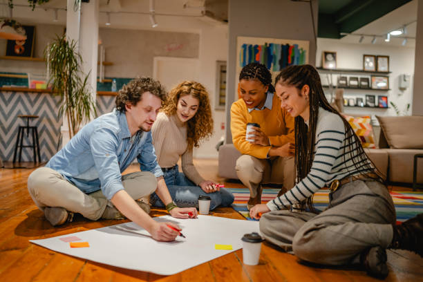 istock multicultural colleagues gather around a large paper on a wooden floor 2197249780