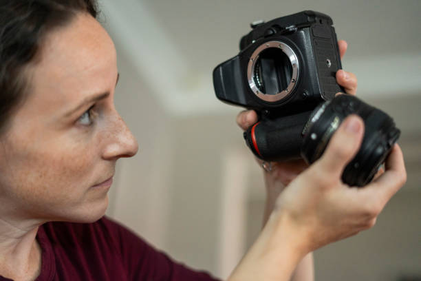 Close-up of female photographer maintaining a DSLR camera lens at the studio