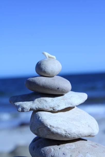 istock Stacked stones on a beach with a blue sky. 2197251095