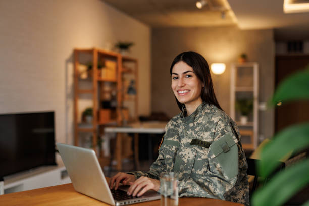 istock Smiling female soldier working on laptop at home 2197254138