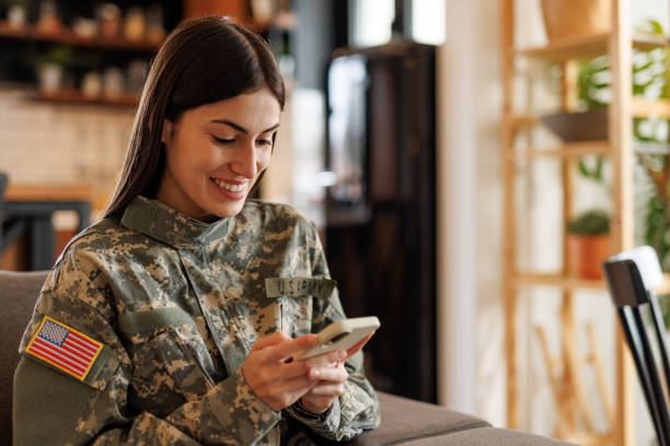 istock Smiling US Army soldier using mobile phone at home 2197254192