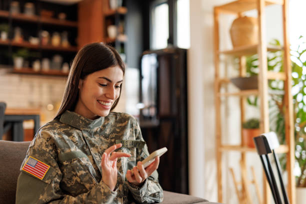 istock Smiling US Army soldier using mobile phone at home 2197254198