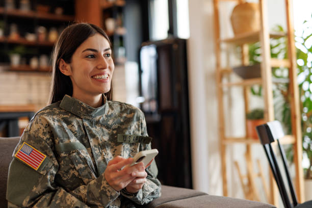 istock Smiling US Army soldier using mobile phone at home 2197254213
