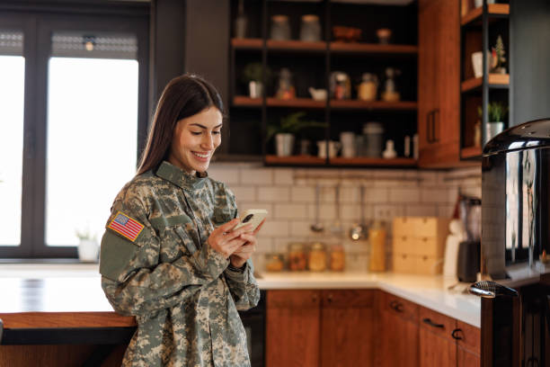 istock Happy US Soldier Woman Using Mobile Phone in Kitchen 2197254236