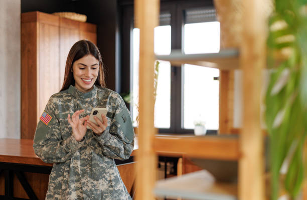 istock Smiling female soldier using mobile phone at home 2197254247