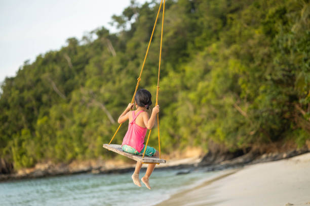 istock Back View of Swinging Child at Beach 2197258788