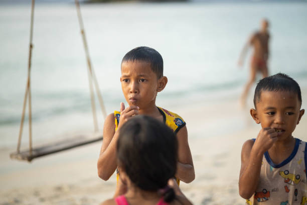 A group of children stand together, enjoying snacks and a playful interaction, capturing the essence of childhood friendships at the beach.