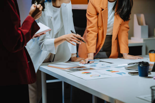 istock Businesswomen are working together, analyzing financial charts and reports, discussing strategies, and collaborating on a project in a modern office environment 2197260867