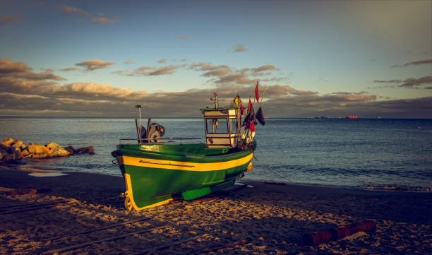 Old fisher boat on the sandy beach. Beautiful sunset seascape on the Baltic Sea coast