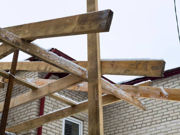 istock Workers are constructing a structure with wooden beams against a backdrop of snow and a brick building on a cold day 2197269361