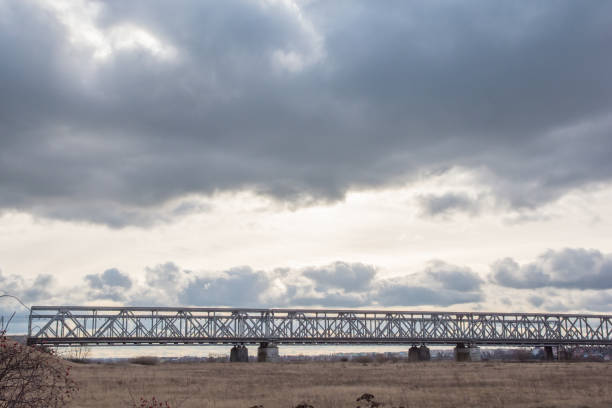 A horizontal color photo depicting a railway bridge over the Vistula River near the city of Tczew in Poland against a cloudy sky.
