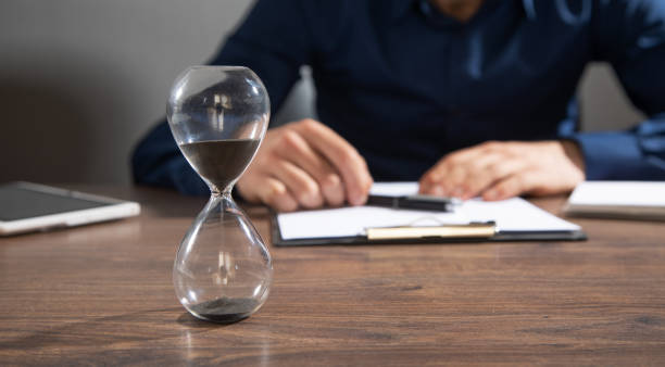 istock Businessman working at office with a hourglass on the table. 2197278424
