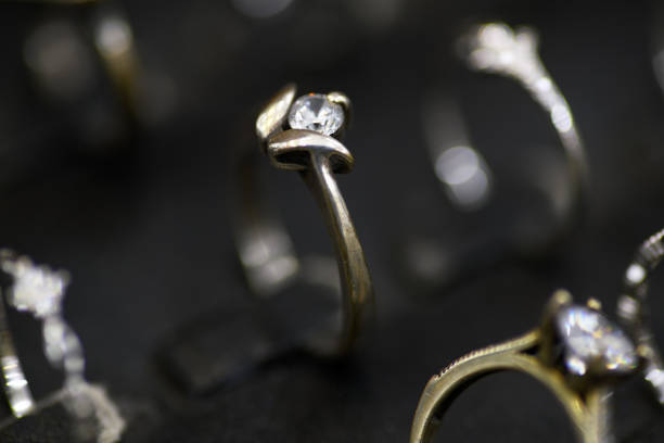 A detailed close-up of a stunning silver solitaire ring featuring a sparkling diamond centerpiece, elegantly displayed among other jewelry pieces in a luxury setting.