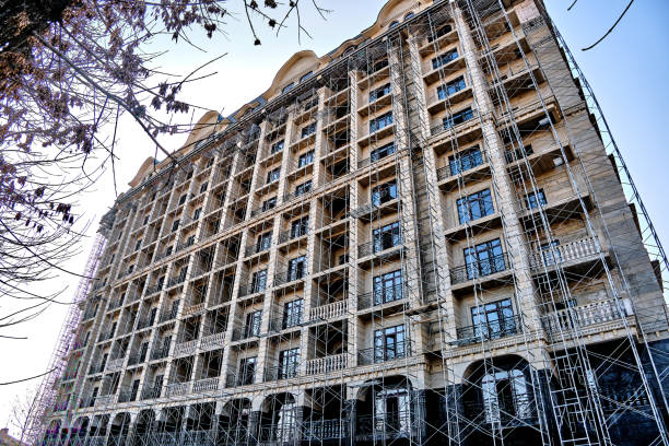 Facade of a multi-story building under construction with scaffolding and balconies.