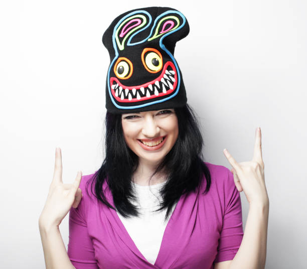Playful young woman in funny hat with rabbit, studio shot