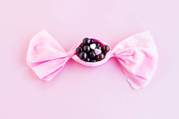 Dark ball chocolates designed in the shape of candy bonbon on a pink surface,above view