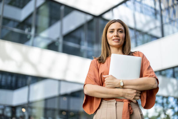 istock Confident Businesswoman Holding Laptop in Modern Setting 2197308476