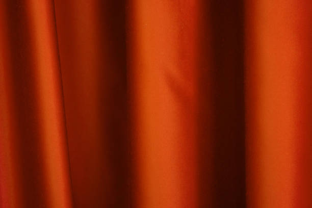istock Vibrant orange curtain drapes elegantly in soft light during an indoor gathering 2197308515