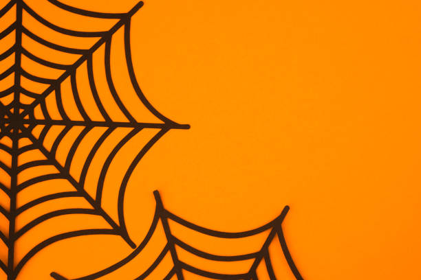 Black spider webs on an orange background create a Halloween atmosphere for festive decorations