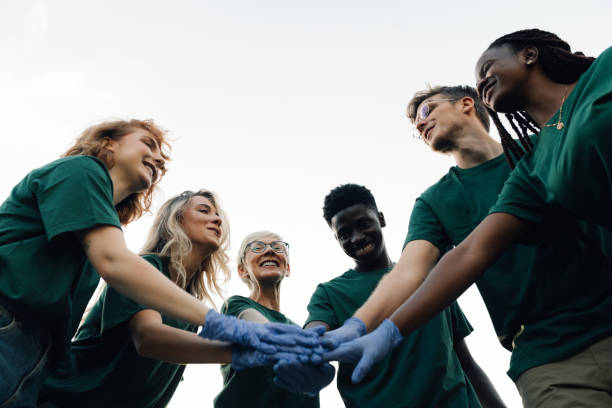 istock Happy volunteers joining hands wearing gloves before volunteering 2197310590