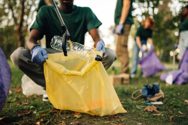 Volunteer picking up plastic bottle in park cleanup