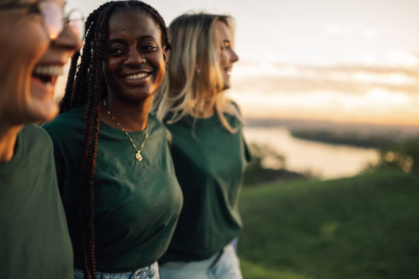 Three women wearing green shirts smiling at sunset