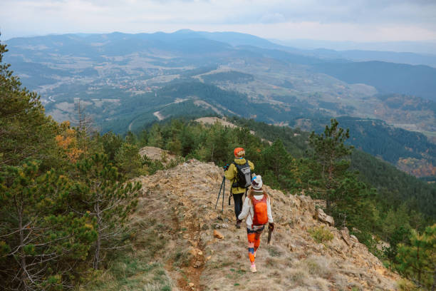 Mom and daughter on top of the mountain range. They are spending a lovely day hiking in the nature. Family bonding and healthy lifestyle concepts.