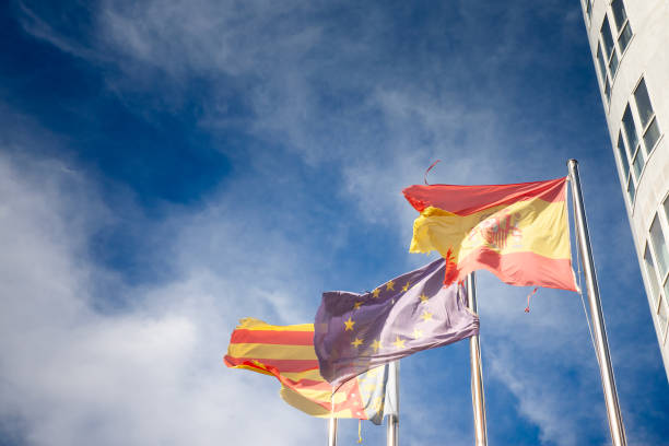 istock Three flagsSpain, the European Union, and Comunidad Valencianaflutter side by side, representing cultural unity and regional pride against a clear sky. Spain is a member of the European union. 2197316440