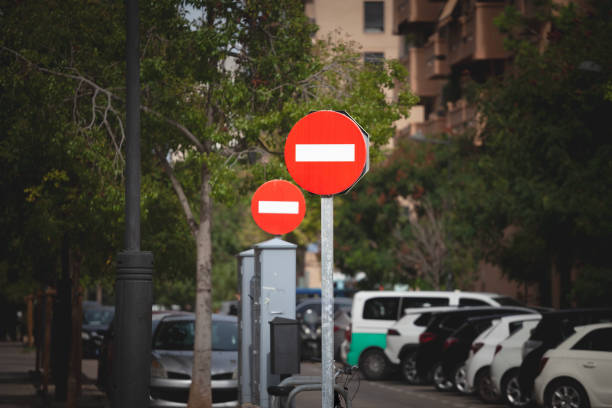 Selective blur on a bright red no-entry sign signals a wrong way on this one-way street by european standards, taken in spain, in valencia. Drivers must heed the prohibition in the urban environment.