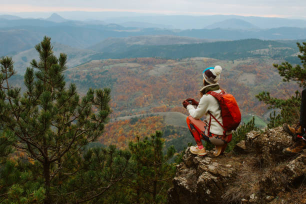 Gen Z woman hiking in the nature, going for the top of the mountain range, enjoys the views and fresh air. Healthy lifestyle concepts in nature.
