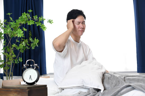ベッドに頭を抱えている若いアジア人男性 - うつ病 日本人 ストックフォトと画像