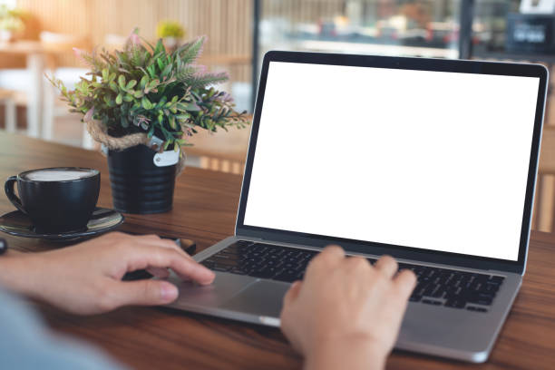 istock Mockup blank white screen laptop computer. Woman working, using laptop computer on wooden table with empty screen for advertising, template for web deign or social media marketing, freelance work 2197328093