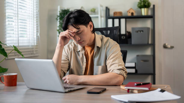 istock A serious, stressed Asian businessman is concerned about the deadline, suffering from a headache. 2197330044
