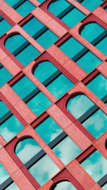 istock Modern Architectural Composition - Diagonal facade with bold red arches contrasting against vibrant teal glass, capturing a dynamic interplay of geometry and color. Perfect for design showcases, architectural branding, or creative inspiration 2197335719