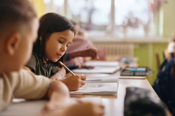 istock Schoolgirl drawing in a notebook during a class in the classroom. 2197345164